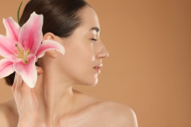 Photo of Beautiful woman after spa treatment with lily flower on beige background, closeup. Space for text
