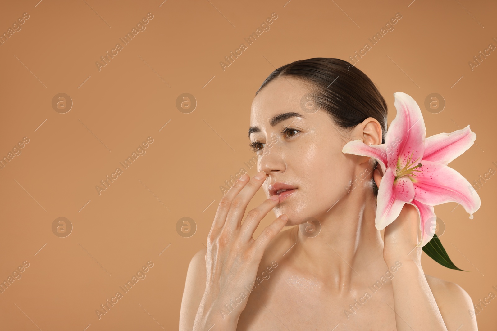 Beautiful woman after spa treatment with lily flower on beige background. Space for text Photo of Beautiful woman after spa treatment with lily flower on beige background. Space for text