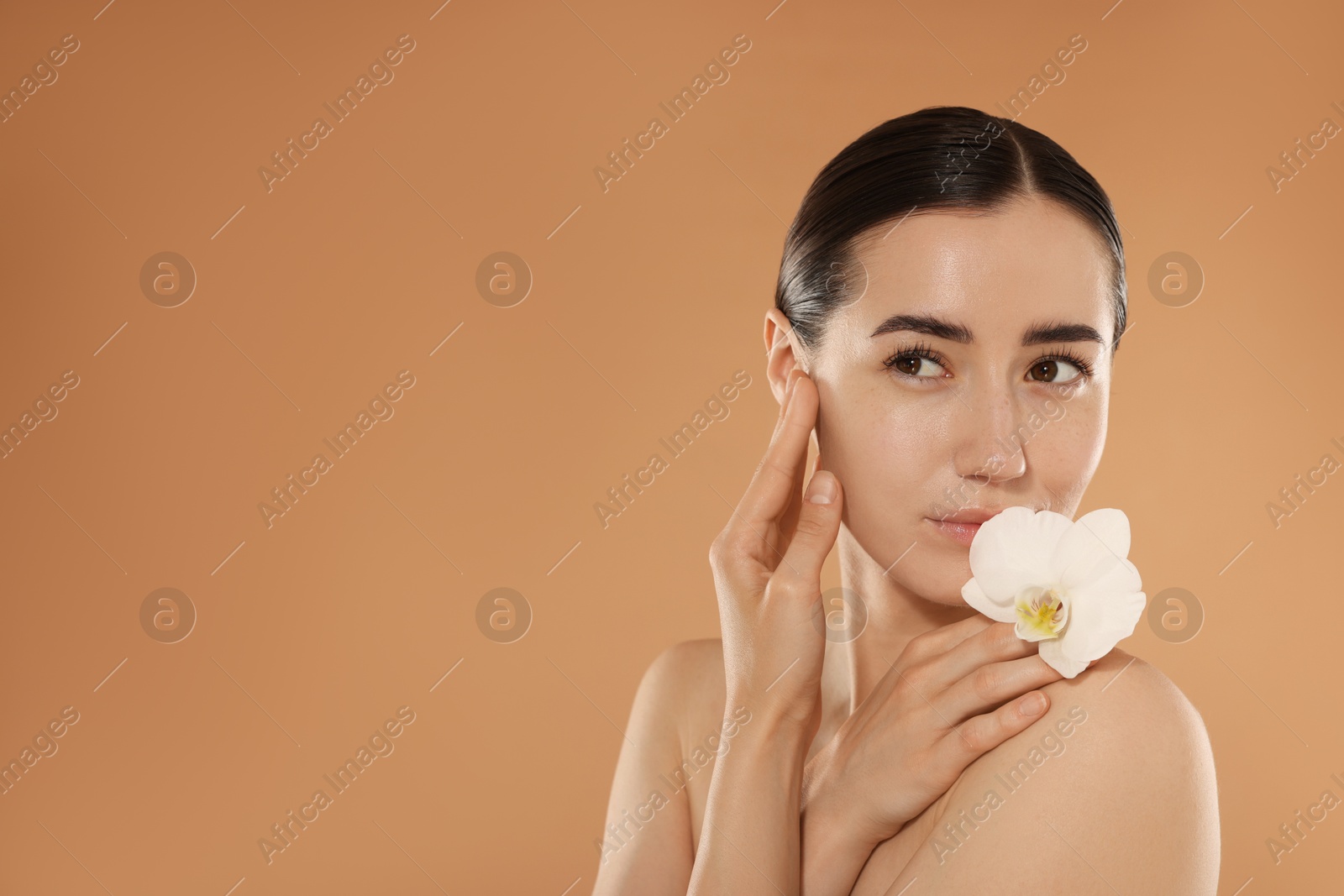Beautiful woman after spa treatment with orchid flower on beige background. Space for text Photo of Beautiful woman after spa treatment with orchid flower on beige background. Space for text