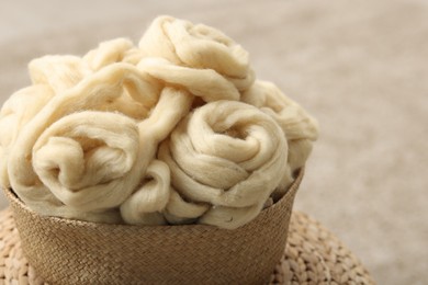 Photo of Felting wool and knitting yarn in wicker basket indoors, closeup. Space for text