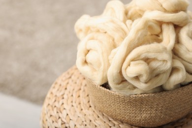 Photo of Felting wool and knitting yarn in wicker basket indoors, closeup. Space for text