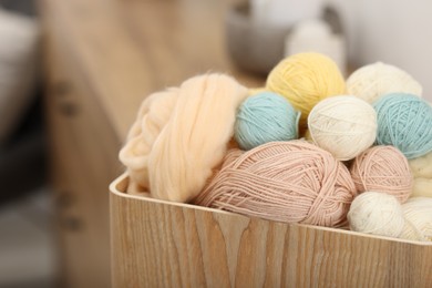 Photo of Felting wool and knitting yarn in wooden basket indoors, closeup