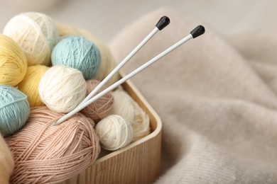 Photo of Felting wool and knitting yarn in wooden basket on fabric, closeup. Space for text