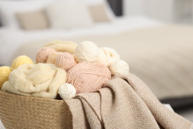 Photo of Felting wool and knitting yarn in wicker basket indoors, closeup