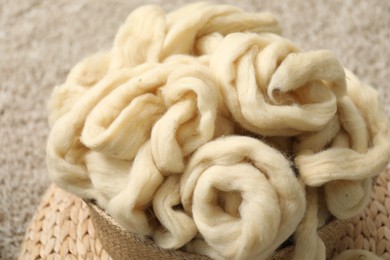 Photo of Felting wool and knitting yarn in wicker basket indoors, closeup