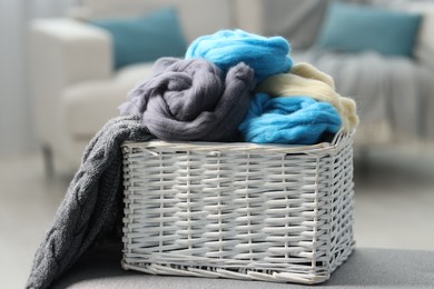 Photo of Soft felting wool in wicker basket on ottoman indoors, closeup