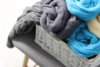 Photo of Soft felting wool in wicker basket on light grey background, closeup