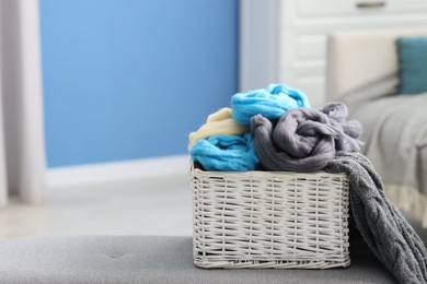 Photo of Soft felting wool in wicker basket on ottoman indoors, closeup. Space for text