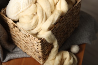 Photo of Soft felting wool in wicker basket on chair indoors, closeup