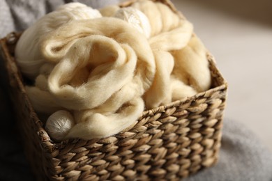 Photo of Soft felting wool in wicker basket on chair indoors, closeup