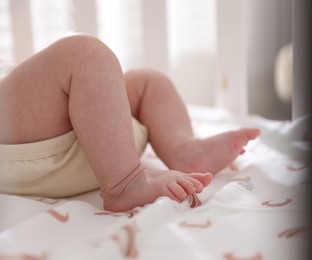 Photo of Cute newborn baby lying in crib, closeup