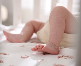 Photo of Cute newborn baby lying in crib, closeup