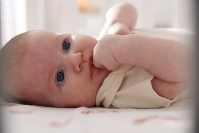 Photo of Cute newborn baby lying in crib, closeup