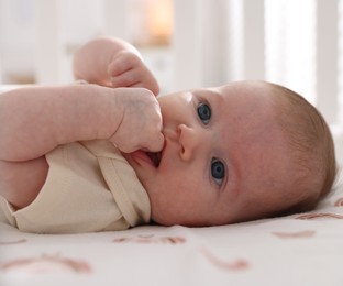 Photo of Cute newborn baby lying in crib, closeup