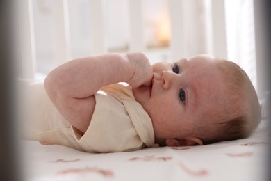Photo of Cute newborn baby lying in crib, closeup