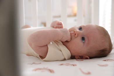 Photo of Cute newborn baby lying in crib, closeup