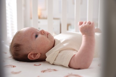 Photo of Cute newborn baby lying in crib, closeup