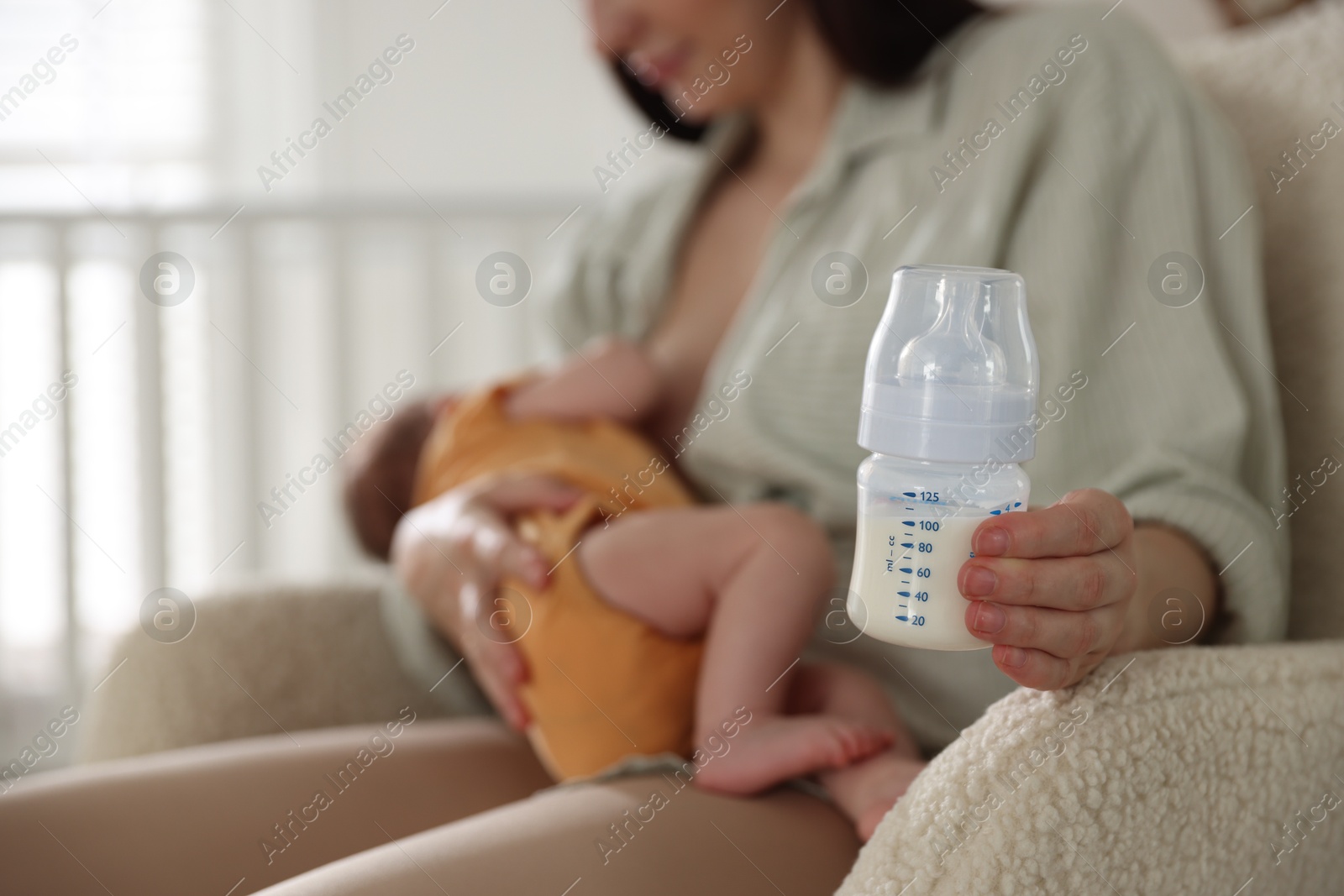 Mother with bottle of milk breastfeeding her newborn baby at home, selective focus Photo of Mother with bottle of milk breastfeeding her newborn baby at home, selective focus