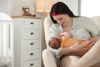Photo of Mother breastfeeding her newborn baby at home. Space for text