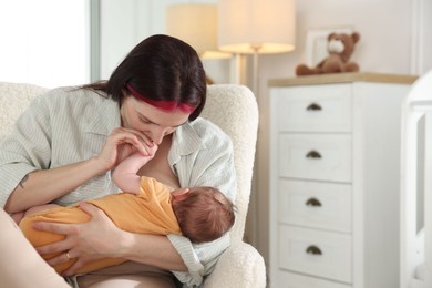 Photo of Mother breastfeeding her newborn baby at home. Space for text