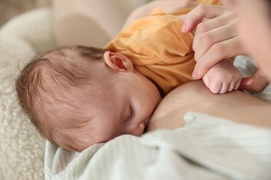 Photo of Mother breastfeeding her newborn baby at home, closeup