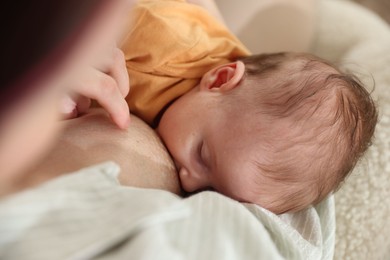 Photo of Mother breastfeeding her newborn baby at home, closeup