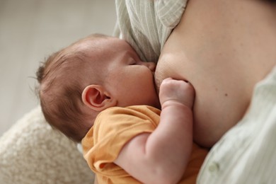 Photo of Mother breastfeeding her newborn baby at home, closeup