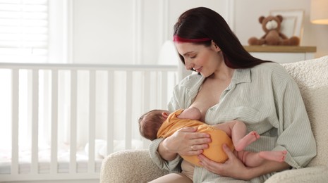 Photo of Mother breastfeeding her newborn baby at home. Space for text