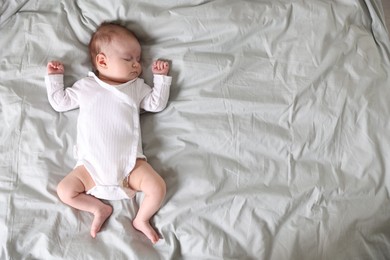 Photo of Cute newborn baby sleeping on bed, top view. Space for text