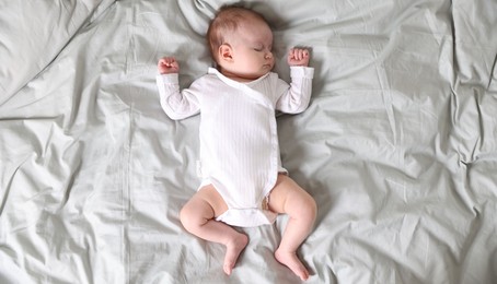 Photo of Cute newborn baby sleeping on bed, top view