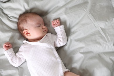 Photo of Cute newborn baby sleeping on bed, top view. Space for text