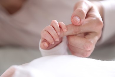 Photo of Mother holding her baby's hand indoors, closeup