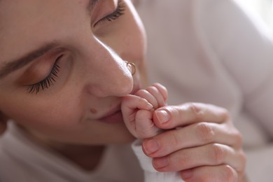 Photo of Mother kissing her baby's hand indoors, closeup