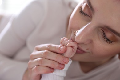 Photo of Mother kissing her baby's hand indoors, closeup