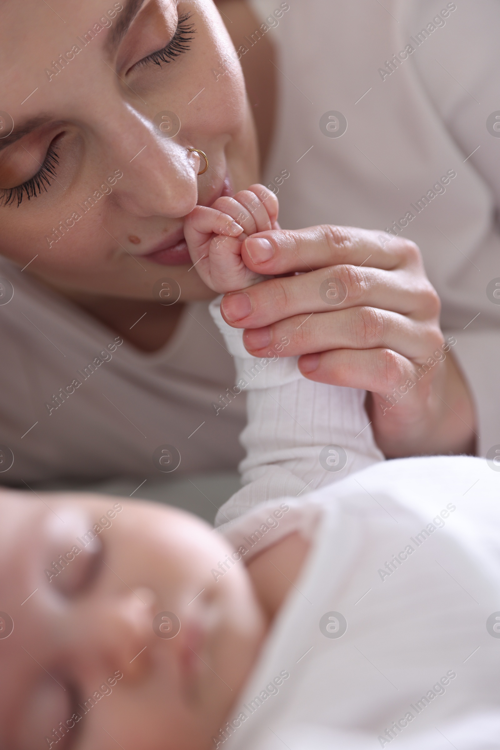Mother kissing her baby's hand indoors, closeup Photo of Mother kissing her baby's hand indoors, closeup