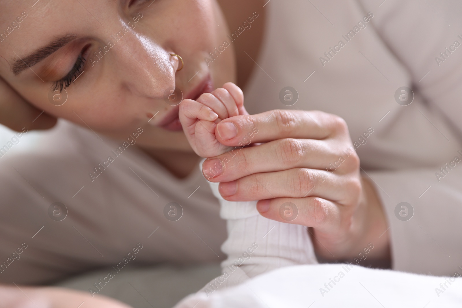 Mother kissing her baby's hand indoors, closeup Photo of Mother kissing her baby's hand indoors, closeup