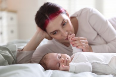 Photo of Mother kissing her baby's hand on bed at home