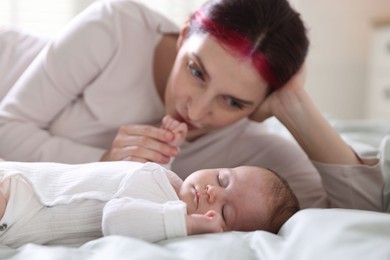 Photo of Mother kissing her baby's hand on bed at home
