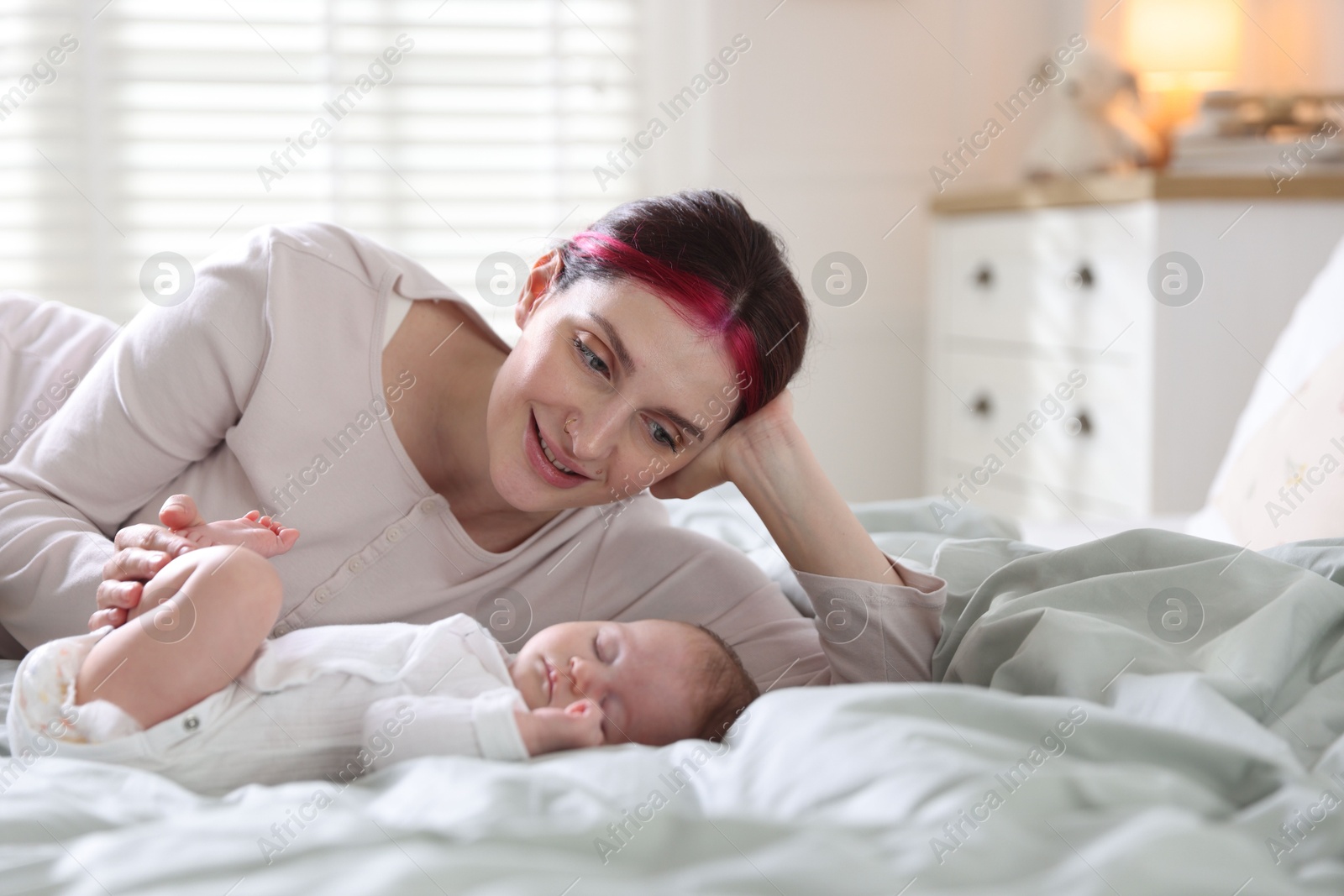 Mother putting her cute newborn baby to sleep on bed at home Photo of Mother putting her cute newborn baby to sleep on bed at home