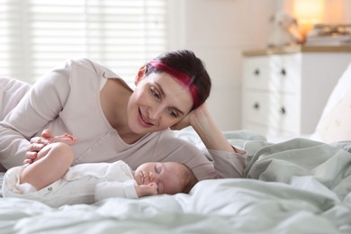 Photo of Mother putting her cute newborn baby to sleep on bed at home