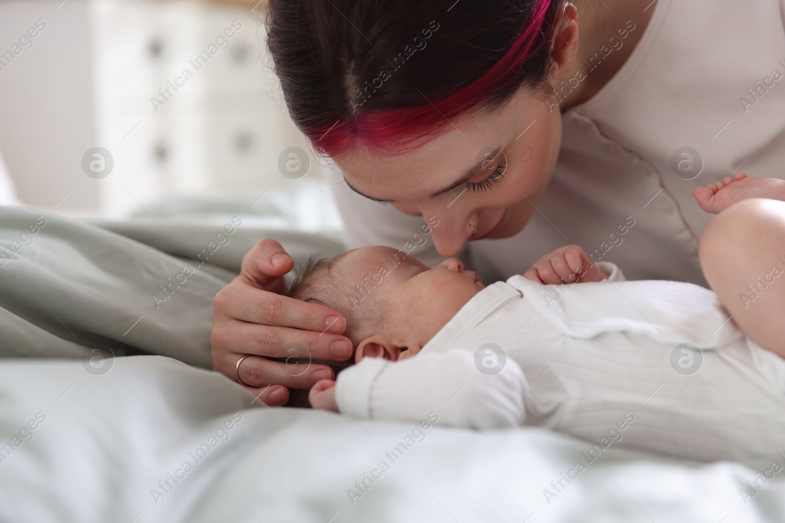 Mother putting her cute newborn baby to sleep on bed at home, closeup Photo of Mother putting her cute newborn baby to sleep on bed at home, closeup