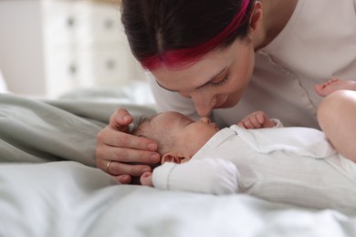 Photo of Mother putting her cute newborn baby to sleep on bed at home, closeup