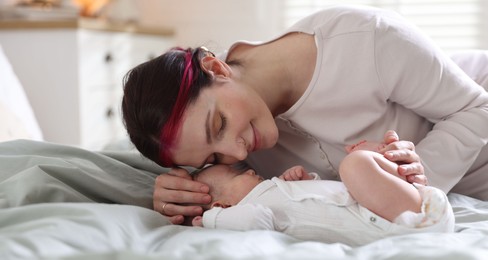 Photo of Mother putting her cute newborn baby to sleep on bed at home