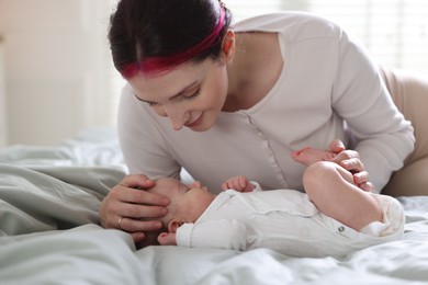 Photo of Mother putting her cute newborn baby to sleep on bed at home