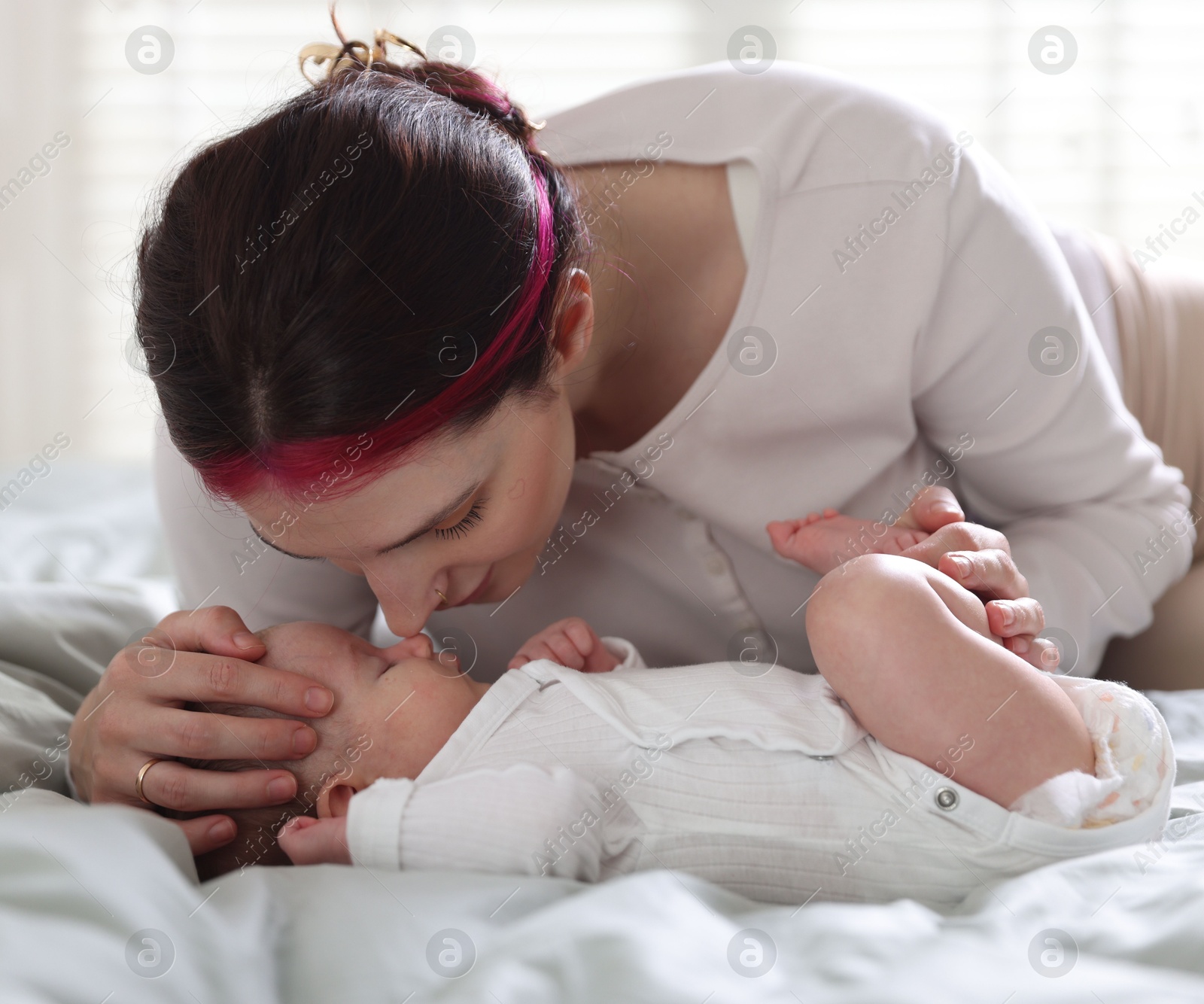 Mother putting her cute newborn baby to sleep on bed at home Photo of Mother putting her cute newborn baby to sleep on bed at home