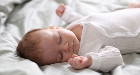 Photo of Cute newborn baby sleeping on bed, closeup