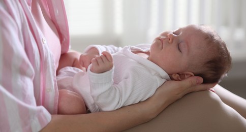 Photo of Mom holding her sleeping newborn baby at home, closeup