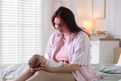 Photo of Mother putting her cute newborn baby to sleep on bed at home