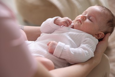 Photo of Mom holding her sleeping newborn baby at home, closeup