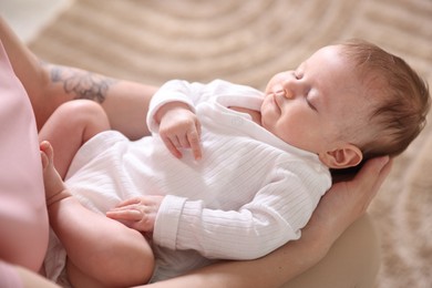 Photo of Mom holding her sleeping newborn baby at home, closeup